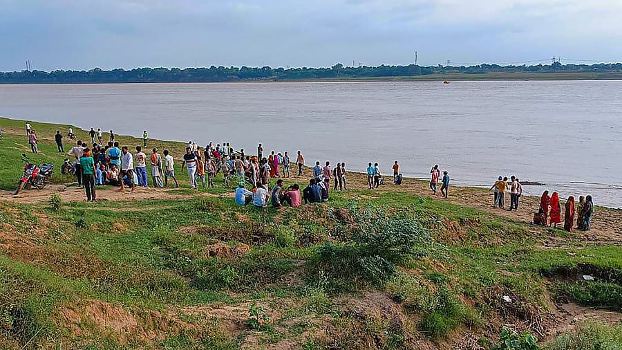 People gather along the banks of Yamuna river after a boat capsized, at Marka area in Banda district, Thursday, Aug. 11, 2022. Several people are feared dead. Credit: PTI Photo