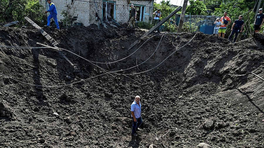 A man stands inside a crater left by a Russian missile strike in the settlement of Kushuhum. Credit: Reuters Photo