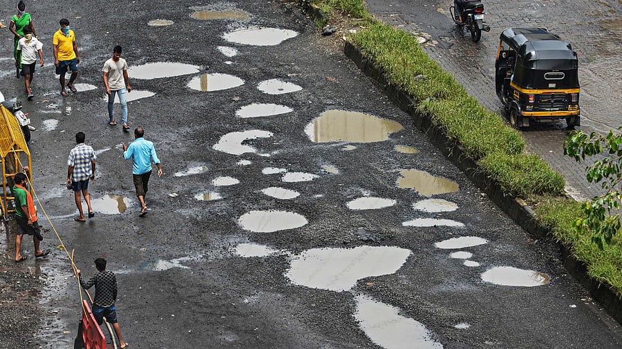 People walk through a road filled with potholes after heavy monsoon rains in Mumbai on August 18, 2020. Credit: AFP Photo
