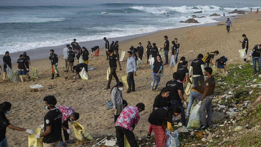 Volunteers pick up trash from a sea beach during a beach clean-up campaign organised by the government of Andhra Pradesh in association with `Parley for the Oceans’ a member of the Global Alliance for a Sustainable Planet that planned a beach clean-up programme on a stretch of 30 kilometres with over 20,000 volunteers in Visakhapatnam on August 26, 2022. Credit: AFP Photo