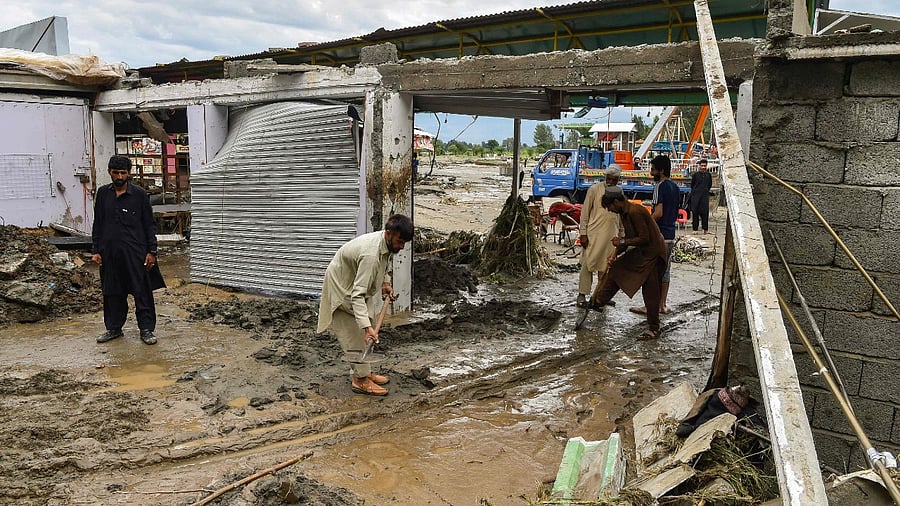 People remove mud that came with the deluge from near their their damaged shops following heavy monsoon rains in Mingora, a town in the Pakistan's northern Swat Valley. Credit: AFP Photo