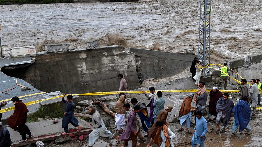 People gather in front of a road damaged by flood waters following heavy monsoon rains in Madian area in Pakistan's northern Swat Valley on August 27. Credit: AFP Photo