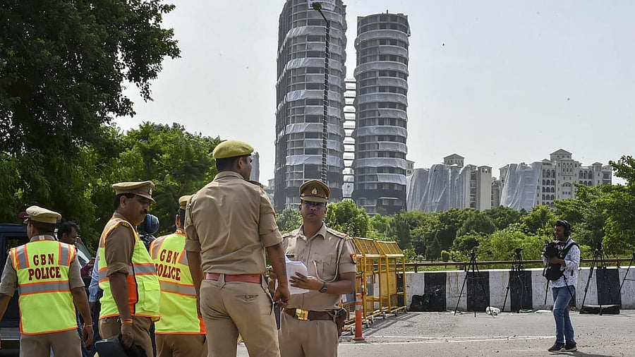 Police personnel keep a watch from a flyover, ahead of the demolition of Supertech twin towers. Credit: PTI Photo