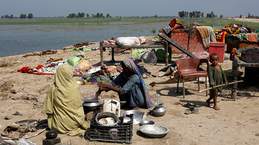 Women prepare food beside their belongings as they take refuge on a higher ground, following rains and floods during the monsoon season in Gari Yasin, Shikarpur, Pakistan August 31. Credit: Reuters Photo