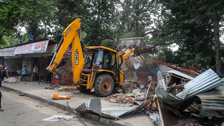 A bulldozer of the Lucknow Municipal Corporation razes illegal shops in front of the Samajwadi Party office. Credit: PTI Photo