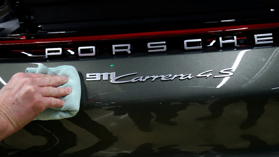 An employee of German car manufacturer Porsche fixes a Porsche 911 Carrera 4S label at the Porsche factory in Stuttgart-Zuffenhausen. Credit: Reuters Photo