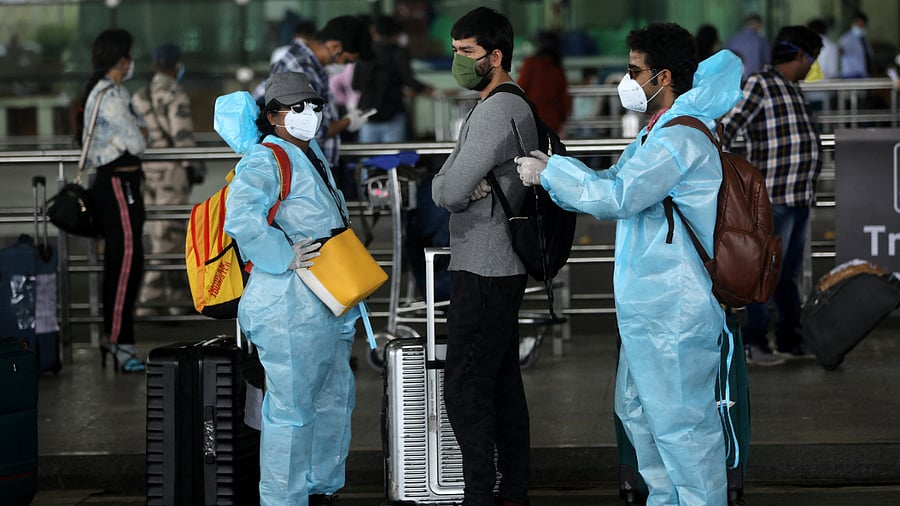 Passengers wear personal protective equipment (PPE) as they stand in a queue to enter Chhatrapati Shivaji International Airport, Mumbai, May 25, 2020. Credit: Reuters File Photo