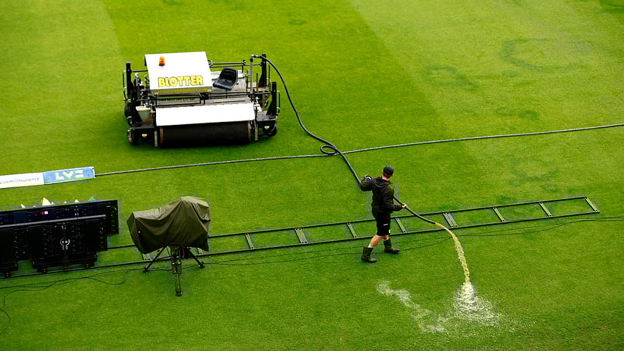 Groundstaff work on the pitch as rain delays the start of play. Credit: Reuters Photo