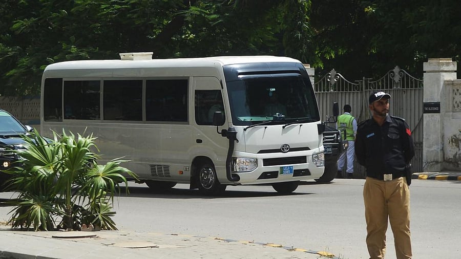 Security personnel stand guard as England cricketers and team officials travel on a bus upon their arrival in Karachi. Credit: AFP Photo