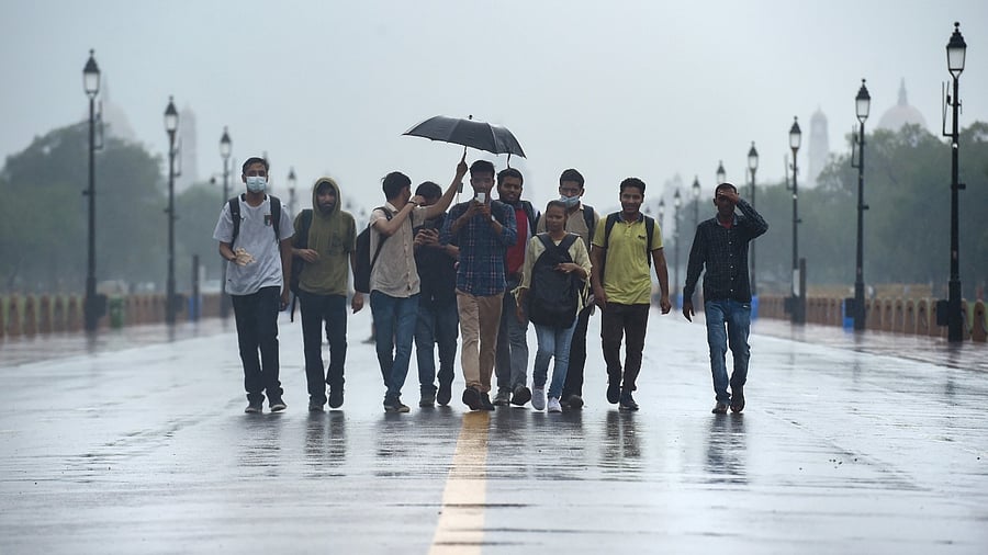  Youngsters holding an umbrella walk down the Kartavya Path amid rainfall. Credit: PTI Photo