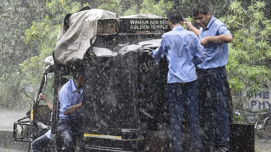 School children travel on an auto-rickshaw during a heavy rainfall. Credit: AFP Photo