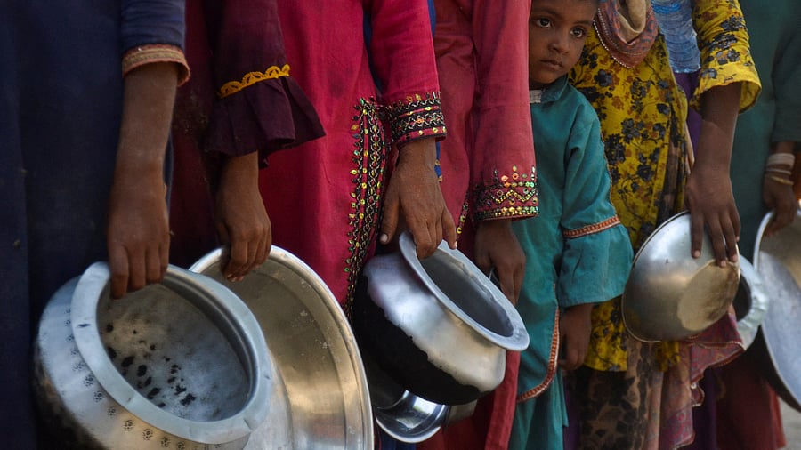 People, displaced because of the floods, gather to receive food handout in a camp, following rains and floods during the monsoon season in Sehwan, Pakistan. Credit: Reuters Photo