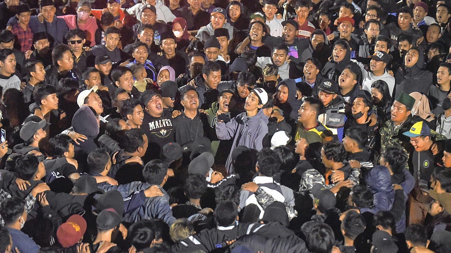 Soccer fans chant slogans during vigil for the victims of Saturday's soccer riots, in Malang, Indonesia, Sunday, Oct. 2, 2022. Credit: AP Photo