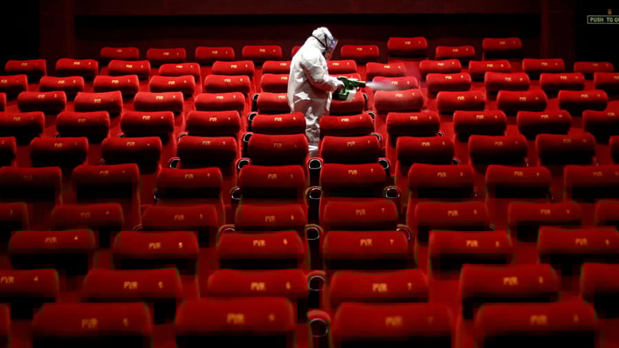 A worker wearing protective gear sprays disinfectant inside an empty PVR multiplex that was closed following the outbreak of the coronavirus disease. Credit: Reuters Photo