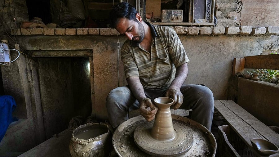 Mohammad Umar Kumar moulds an earthen lamp on a wheel ahead of Diwali at his workshop in Srinagar. Credit: PTI Photo