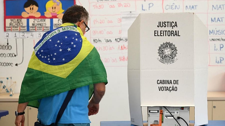 A man with a Brazilian national flag on his shoulders votes at a polling station in Brasilia. Credit: AFP Photo