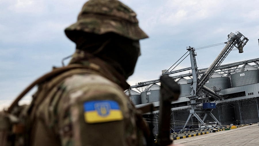 A Ukrainian serviceman stands in front of silos of grain from Odesa Black Sea port. Credit: Reuters Photo