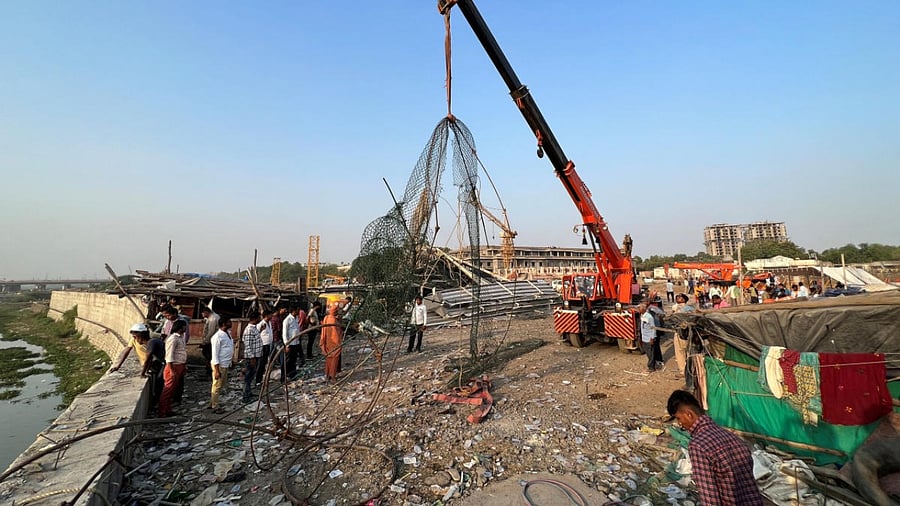 People remove debris after a suspension bridge collapsed in Morbi town. Credit: Reuters Photo