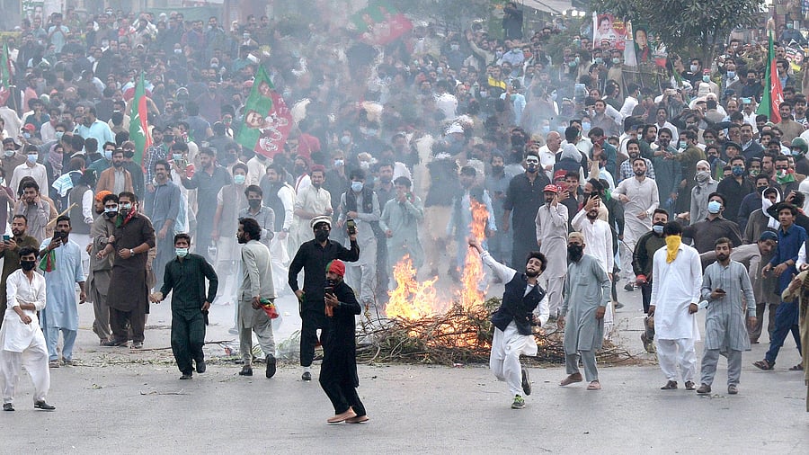 Supporters of former Pakistani Prime Minister Imran Khan's party, 'Pakistan Tehreek-e-Insaf' throw stones toward police officers during a protest to condemn a shooting incident on their leader's convoy, in Rawalpindi. Credit: AP Photo