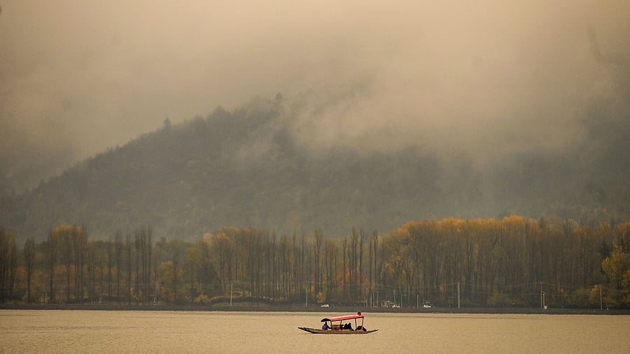 People take a shikara ride in the Dal Lake as it rains in Srinagar. Credit: AFP Photo