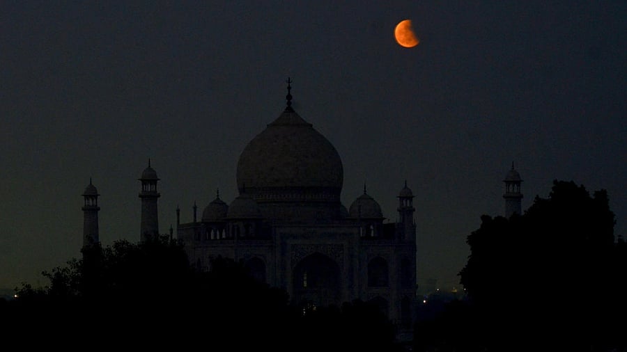 Moon partially covered by the earth's shadow during lunar eclipse, seen behind the Taj Mahal in Agra, Tuesday, Nov. 8, 2022. Credit: PTI Photo