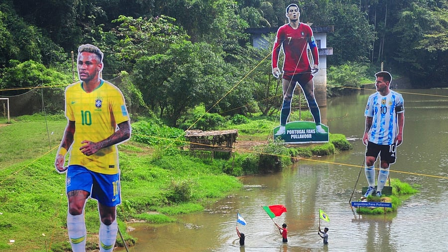 Fans wave flags next to the giant cutouts of players from Brazil's Neymar (L), Portuguese Cristiano Ronaldo (C) and Argentine Lionel Messi, erected by football fans in river Cherupuzha at Kozhikode in India's Kerala state on November 7, 2022, ahead of the Qatar 2022 FIFA World Cup. Credit: AFP Photo