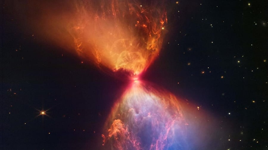 This undated composite handout image from NASA's James Webb Space Telescope Near-Infrared Camera (NIRCam) released by NASA and STScl, shows the Protostar within the dark cloud L1527 with ejections from the star above and below appear orange and blue in infrared view. Credit: AFP Photo