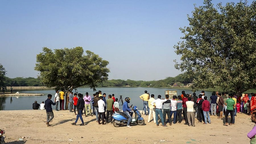 Media personnel and locals near a pond where Aftab Poonawalla, accused in the Mehrauli murder case, is suspected to have dumped his live-in partner Shraddha Walkar's head and some other remains, at Chhatarpur area in New Delhi. Credit: PTI File Photo