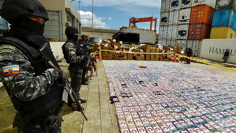 Ecuadorean anti-narcotics police stand guard next to packs of cocaine from a 3-ton shipment seized from a container of bananas, in the port of Guayaquil, Ecuador. Credit: AFP Photo