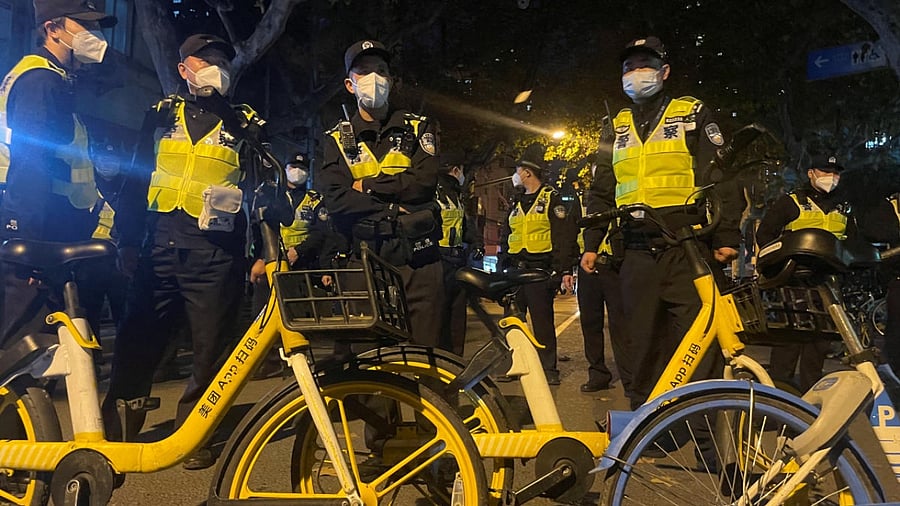 Police officers stand guard during a demonstration against Covid-19 curbs following the deadly Urumqi fire, in Shanghai. Credit: Reuters Photo