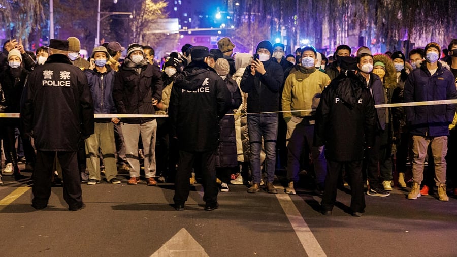 People stand behind a police cordon as they watch a protest over coronavirus disease (COVID-19) restrictions in Beijing. Credit: Reuters Photo