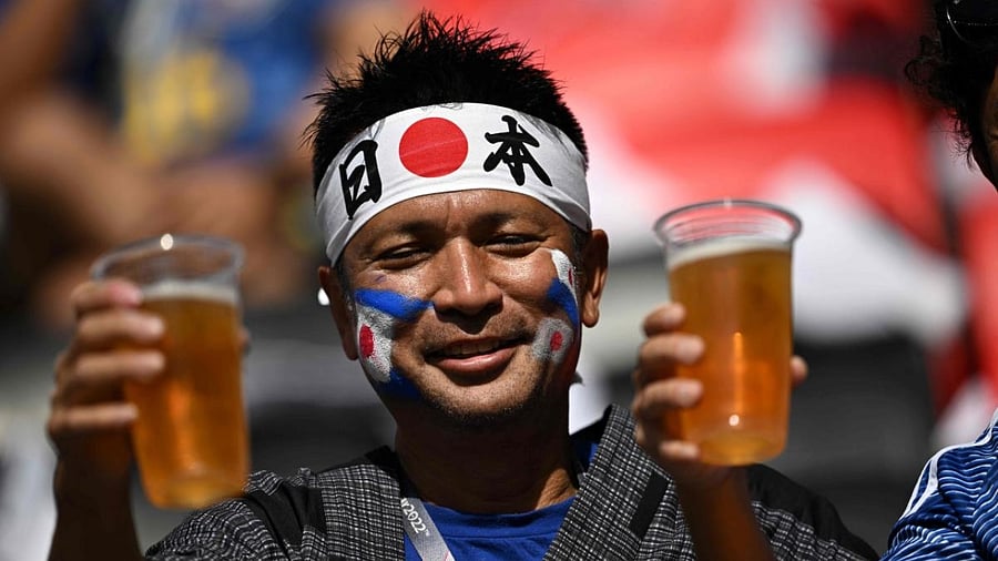 A Japan supporter holds up non-alcohol beer as he cheers ahead of the Qatar 2022 World Cup. Credit: AFP Photo