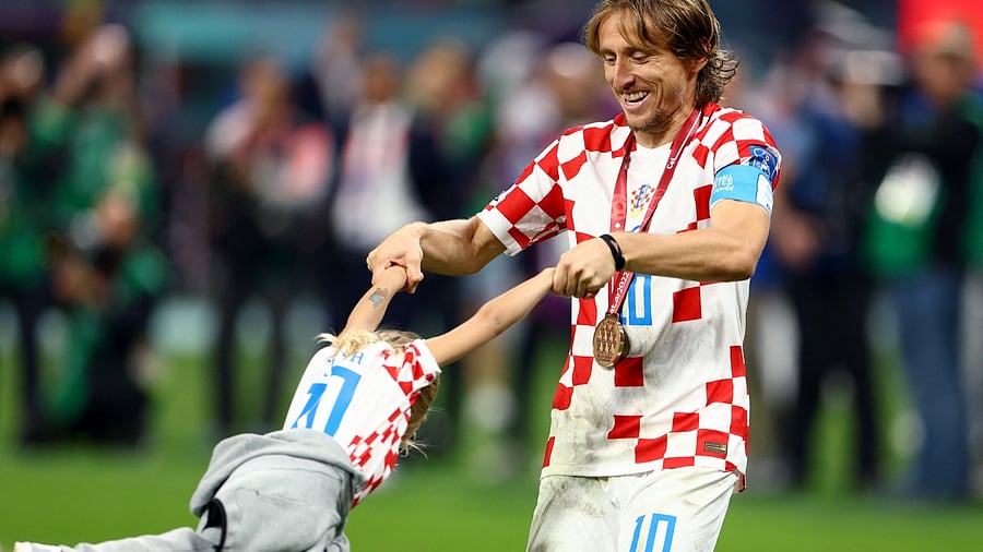 Croatia's Luka Modric wears his medal as he celebrates with a child on the pitch after Croatia finish in third place. Credit: Reuters Photo