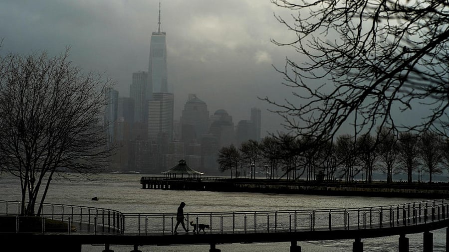 A woman walks her dog in a local park in Hoboken, New Jersey, while storm clouds pass by the One World Trade Center in New York. Credit: Reuters photo