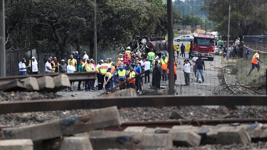 People gather near a burnt out truck at the entrance of the damaged bridge where a gas tanker exploded in Boksburg near Johannesburg. Credit: Reuters Photo