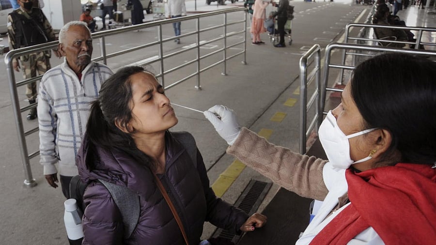 A medic takes swab sample from an air passenger for COVID-19 test at the Birsa Munda International Airport. Credit: PTI