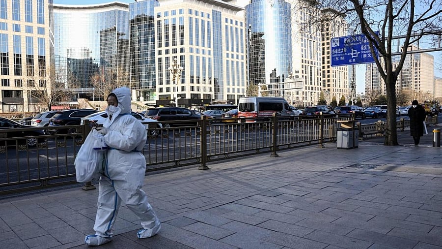 Woman wearing PPE during Covid, walks on the street of Beijing. Credit: AFP Photo