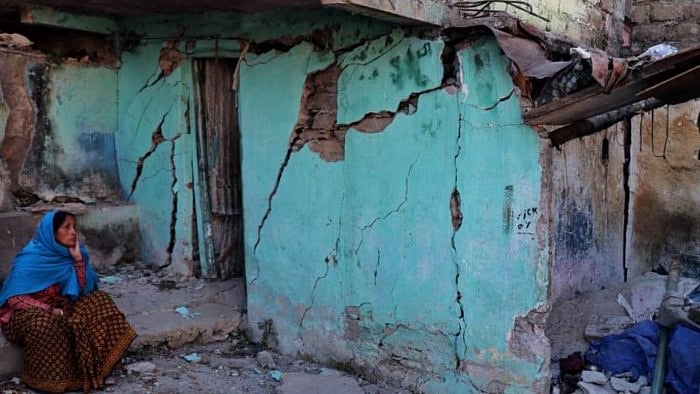 A resident sits next to a cracked wall of her house at Joshimath in Chamoli district of Uttarakhand on January 8, 2023. Credit: AFP Photo