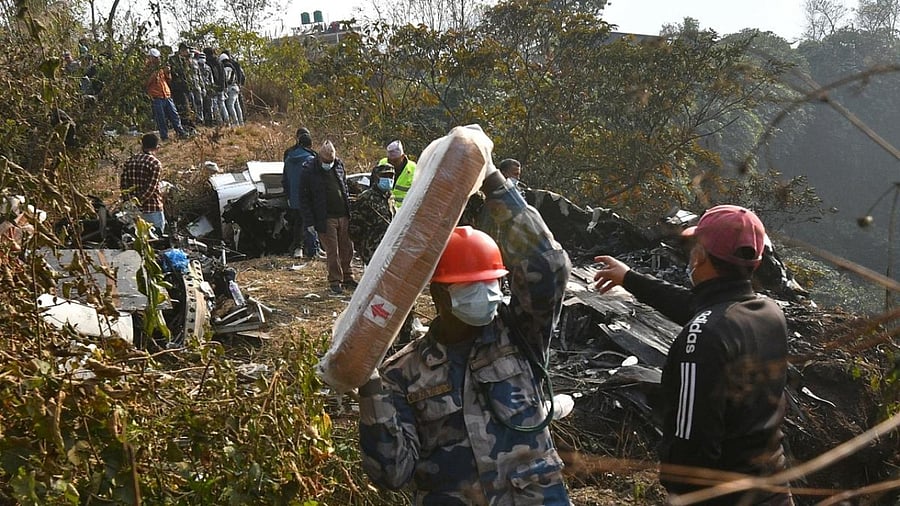 Rescuers inspect the wreckage at the site of a plane crash in Pokhara. Credit: AFP Photo