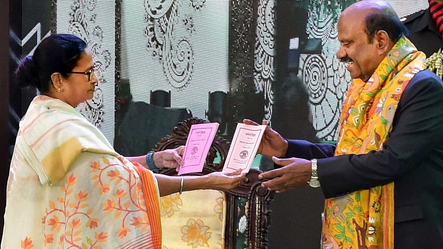 Bengal Governor CV Ananda Bose receives 'Barnaparichay' book from CM Mamata Banerjee during the 'Hatey Khari' event at Raj Bhavan. Credit: PTI Photo