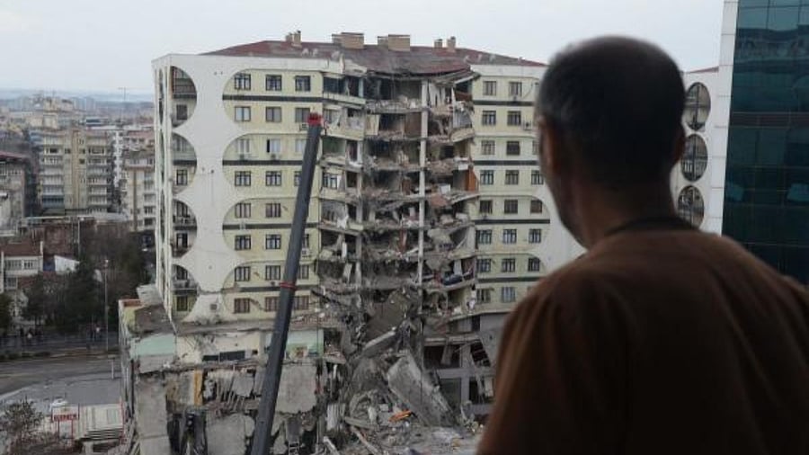 A man looks on at search and rescue operations conducted in the rubble of a collasped building, in Turkey. Credit: AFP Photo