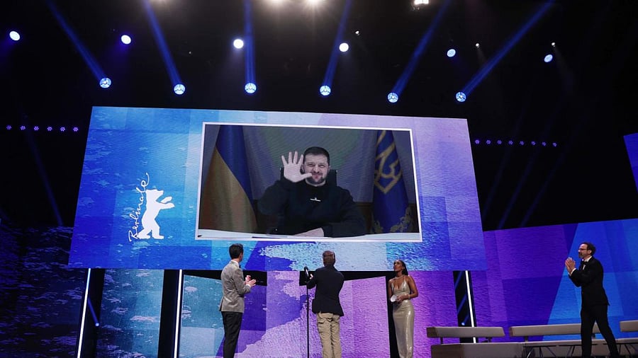 Ukrainian President Volodymyr Zelensky waves after addressin the audience via a video message as Berlinale Artistic Director Carlo Chatrian (R) applauds during the Opening Gala of the Berlinale. Credit: AFP Photo
