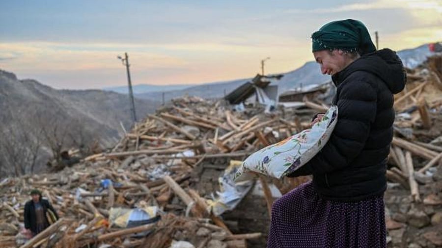 This photograph taken on February 19, 2023, shows a woman crying as she collects her personal belongings atop the rubble of her collapsed house in Yaylakonak village in Adiyaman district, Turkey. Credit: AFP Photo