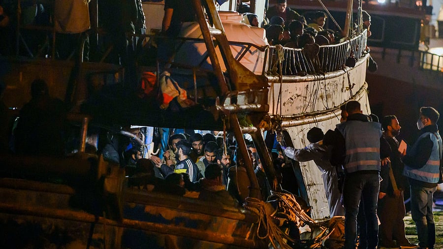 Some of nearly 500 migrants are seen waiting for medical checks on board a fishing boat in the southern Italian port of Crotone, early Saturday, March 11, 2023.  Credit: AP Photo
