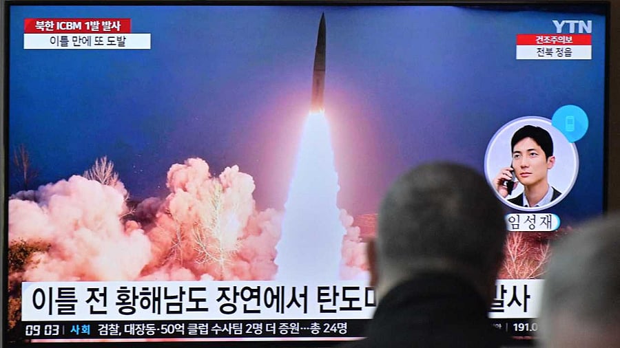 People sit near a television showing a news broadcast with file footage of a North Korean missile test. Credit: AFP Photo