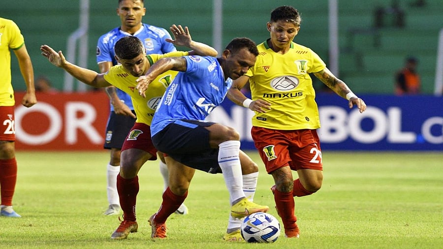 Palmaflor's Argentine midfielder Matias Pisano (L) and midfielder Juan Adrian (R) vie for the ball with Blooming's Venezuelan midfielder Arquimedes Figuera (C) during the Copa Sudamericana first stage football match between Bolivia's Blooming and Bolivia's Atletico Palma Flor, at the Ramón Aguilera Costas stadium in Santa Cruz, Bolivia, on March 9, 2023. Credit: AP Photos