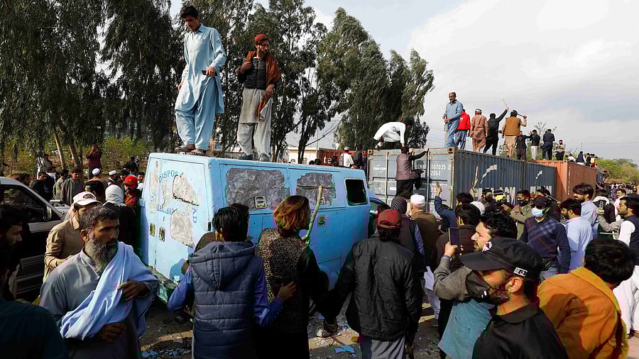 Supporters of former Pakistani Prime Minister Imran Khan climb on shipping containers, placed to block the road, during a clash outside the federal judicial complex in Islamabad. Credit: Reuters Photo