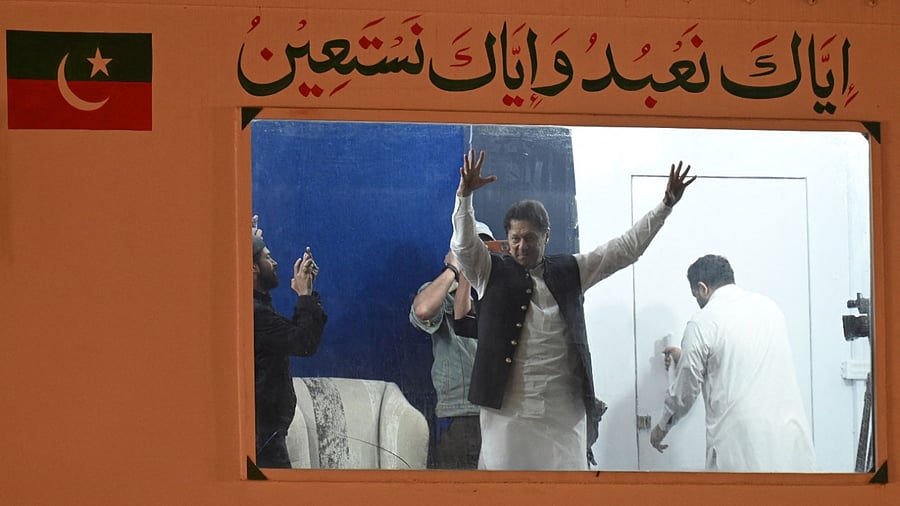 Pakistan's former prime minister Imran Khan raises hands to his supporters from behind a bulletproof shield on arrival at a rally in Lahore. Credit: AFP Photo