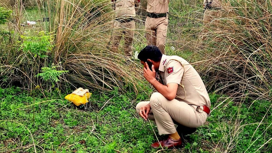 Police personnel recover a package, suspected to have been airdropped by a drone from across the International Border, in Samba district, Jammu and Kashmir. Credit: PTI Photo