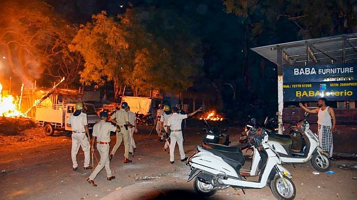 Police personnel at the fire incident site where several shops and vehicles reportedly set ablaze in a clash between two groups at Shastri Nagar area. Credit: PTI Photo